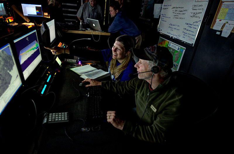 A mapping watchstander and marine ecologist viewing canyon data using Fledermaus software in the NOAA Ship Okeanos Explorer control room.