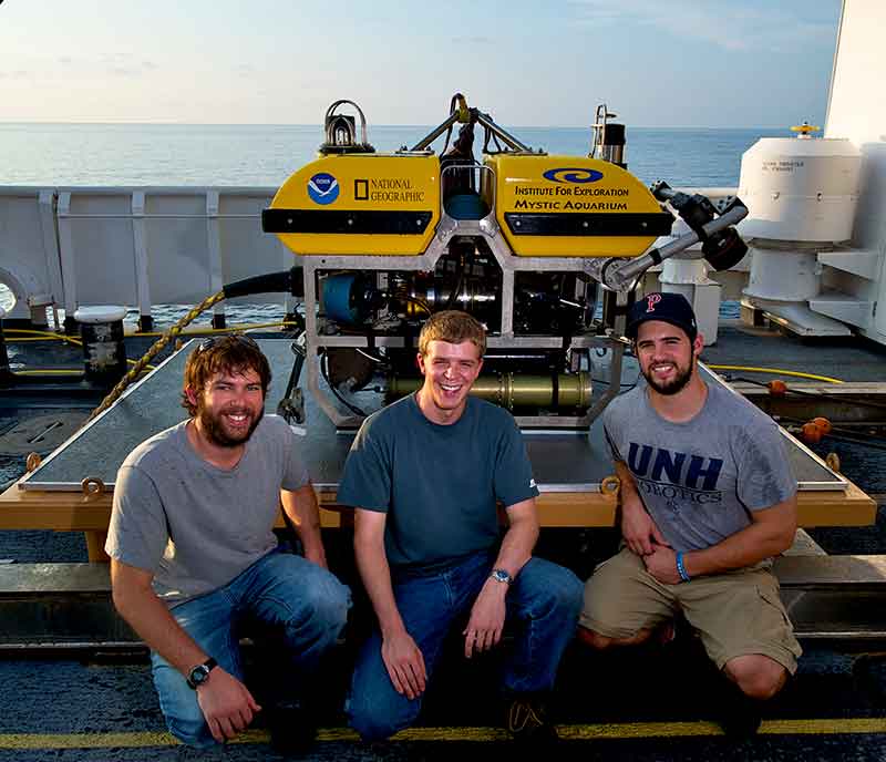 ROV team members Karl McLetchie, Tom Kok, and Joel De Mello (from left to right) pose in front of <em>Little Hercules</em>. Even with the ROV secure on deck, work continues with routine checks and maintenance.