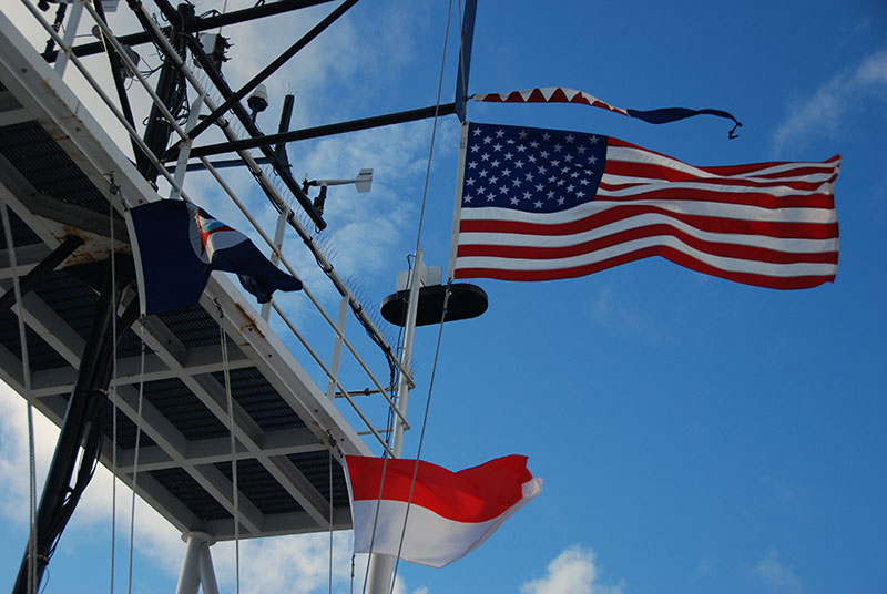 >When a vessel is underway, it is a requirement to fly certain flags. The first is the ensign—the flag of the vessel’s own country. Above the ensign is the commissioning pennant, a symbol of the command of the vessel. Below are the NOAA house flag (left) and the flag of the Republic of Indonesia (right), which represents the country whose waters we are operating in.