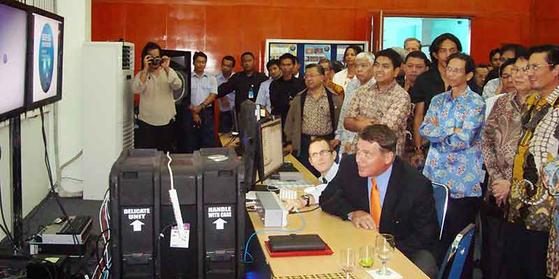 During a visit to the Jakarta Exploration Command Center, U.S. Ambassador Cameron Hume speaks to U.S. and Indonesian representatives onboard NOAA Ship <em>Okeanos Explorer</em>. Minister Fadel of Indonesia’s Ministry of Marine Affairs and Fisheries stands behind him.