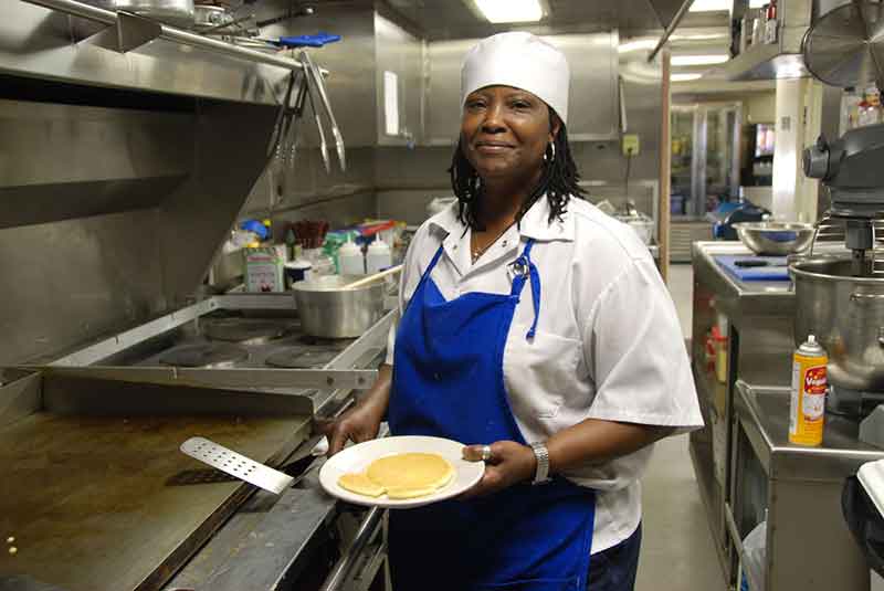 Chief cook Doretha Mackey works long and grueling days in the loud, heated galley, preparing three meals a day as well as snacks and desserts. A must have is her Coca-Cola cake!