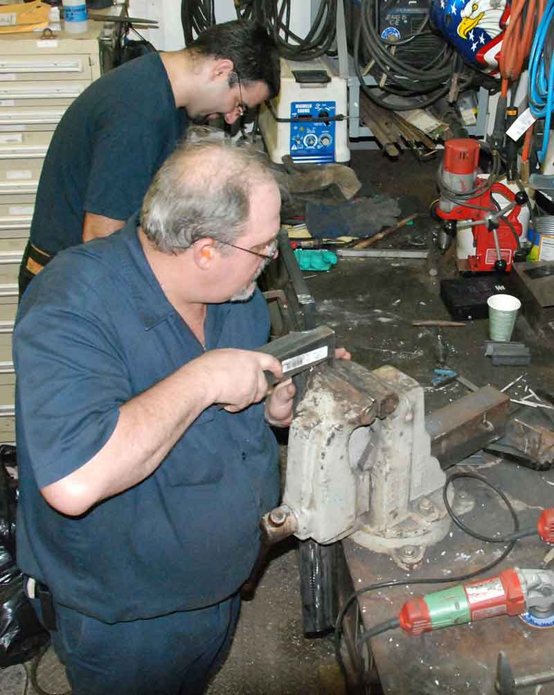 Third assistant engineers Greg Feeney (back) and Tim VanDyke (front) fabricate parts for the ship’s infrastructure.