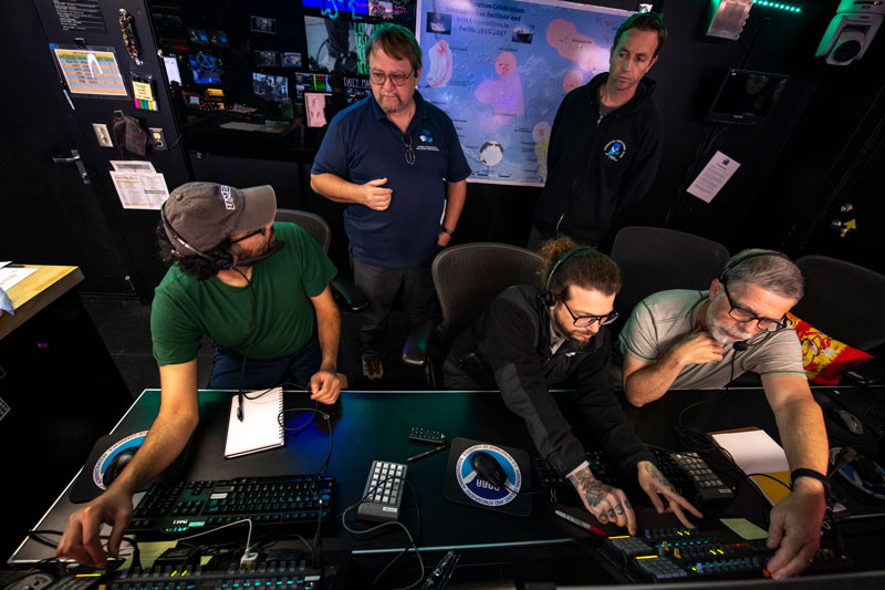 From left to right: Arvind Shantharam, Voyage to the Ridge 2022 Expedition 2 sample data manager; Roland Brian, video engineer with the Global Foundation for Ocean Exploration; Expedition 2 geology science lead Ashton Flinders; Expedition 2 biology science lead Scott France; and expedition manager Derek Sowers in the control room of NOAA Ship Okeanos Explorer.