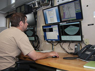 Senior Survey Technician David Moehl at the controls of Hassler’s multi-beam echosounders in the ship’s Survey Lab. Hassler is equipped with several different seabed mapping systems, each optimized for a different depth range.
