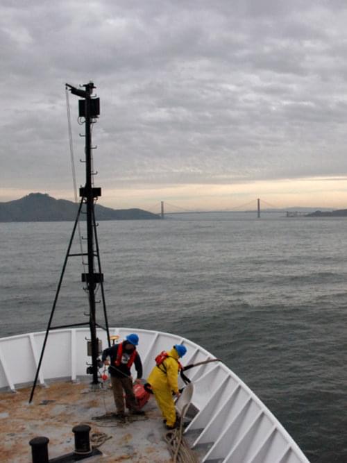 Two deck hands prepare Okeanos Explorer to come into port as she nears the Golden Gate Bridge. The EX1006 “Always Exploring” cruise ended today when the ship came into port in San Francisco harbor.