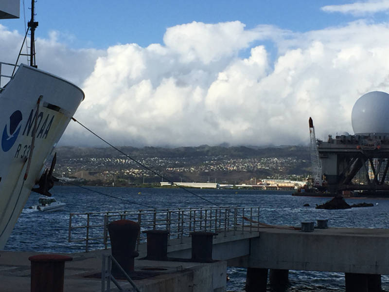 NOAA Ship Okeanos Explorer moored pier side Ford Island with the final resting place of the USS Utah visible just above the waterline.