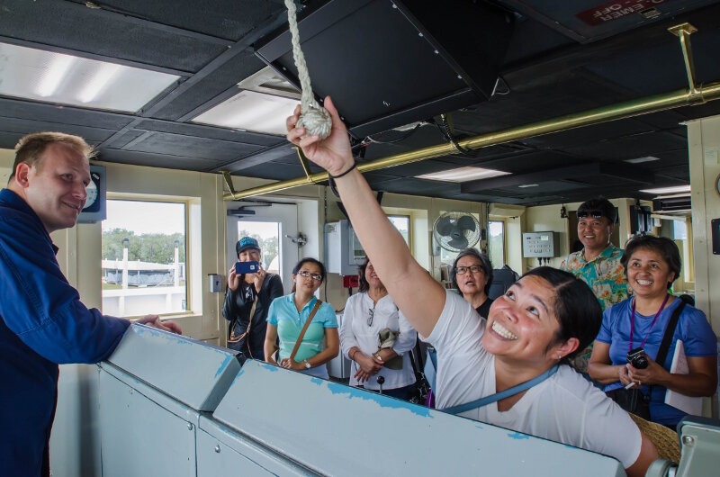 A teacher participant in the “Why Do We Explore” workshop pulls the foghorn of NOAA Ship Okeanos Explorer.