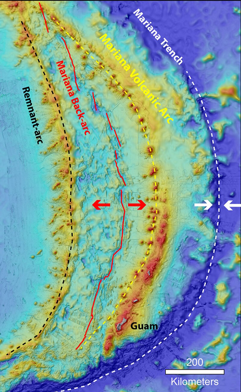 Map showing the locations of the Mariana Trench (white dashed line), Volcanic Arc (yellow dashed line), and back-arc spreading center (red line) and remnant arc (black dashed line).