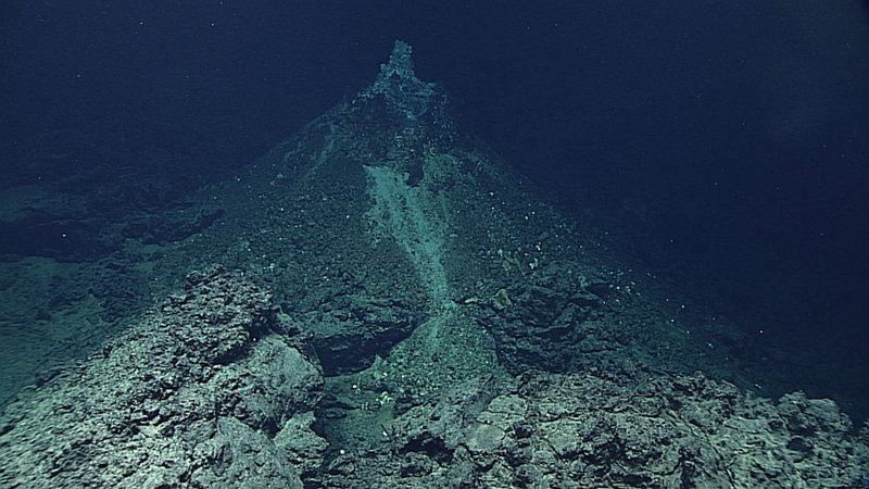 Hydrothermal chimney on top of hydrothermal mound; volcanic rocks in foreground.