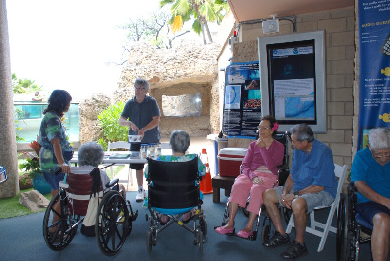 Chris Kelley displays specimens at the Waikiki Aquarium with the live stream in the background.