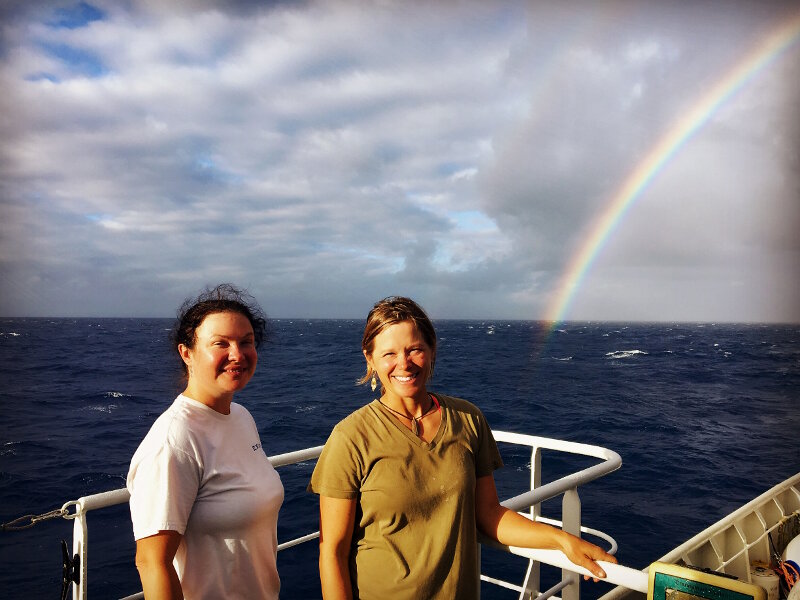 The women of the deck department on NOAA Ship Okeanos Explorer. A squall has passed and left a rainbow behind.
