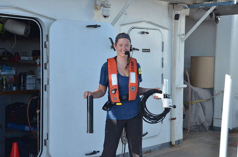 Neah Baechler, a mapping watchstander during a 2017 deep-monument Hawai’ian expedition, prepares to put away the expendable bathythermograph (XBT) probe (left), and the XBT launcher (right) after its deployment. During the expedition, the XBT was manually launched every 2-6 hours in a process called an “XBT cast” to measure water column temperature data down to 760 meters (2,493 feet). This information was used to assist with multibeam mapping.