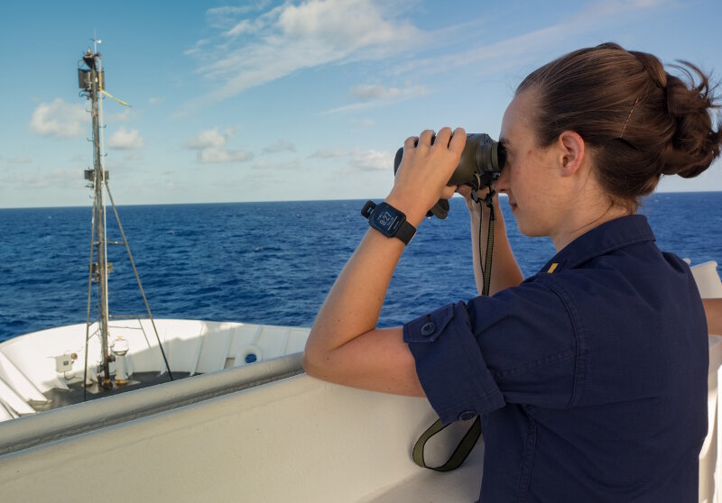 ENS Anna Hallingstad scans the horizon from NOAA Ship Okeanos Explorer.