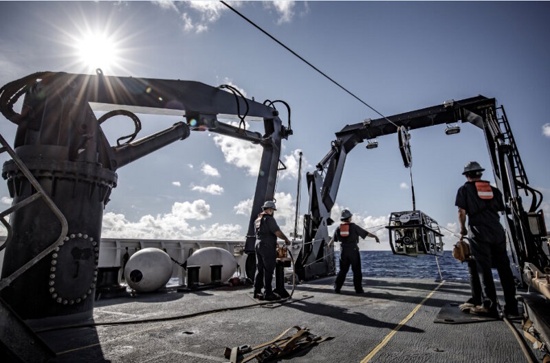 The team launches ROV Seirios onto the back deck of NOAA Ship Okeanos Explorer at sunset