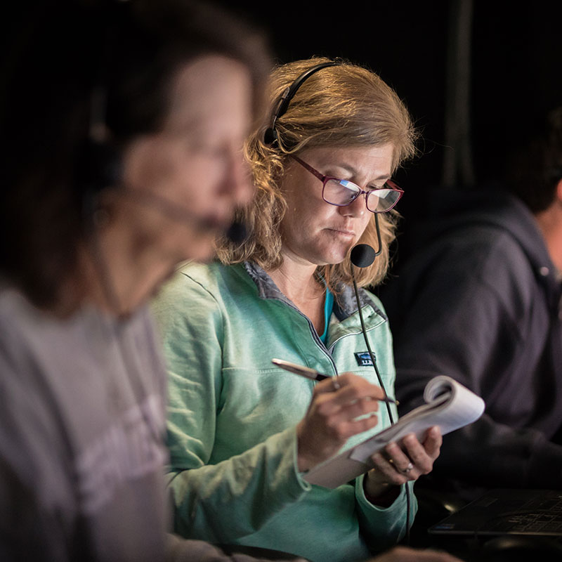Expedition co-science lead and biologist, Cheryl Morrison, in the control room on NOAA Ship Okeanos Explorer taking notes of the species seen during a dive for the Windows to the Deep 2018 expedition.