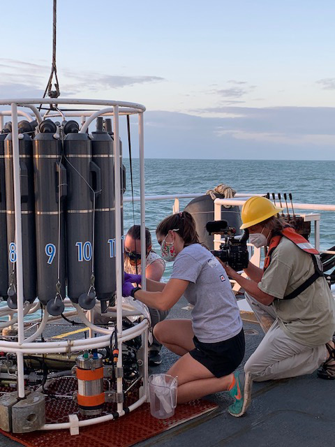 May 15, 2021. Meredith Everett of NOAA’s Northwest Fisheries Science Center (left) and Katharine Egan of NOAA Ocean Exploration (center) gather water samples after a successful CTD cast. Art Howard (right), a videographer with the Global Foundation for Ocean Exploration, documents the work.