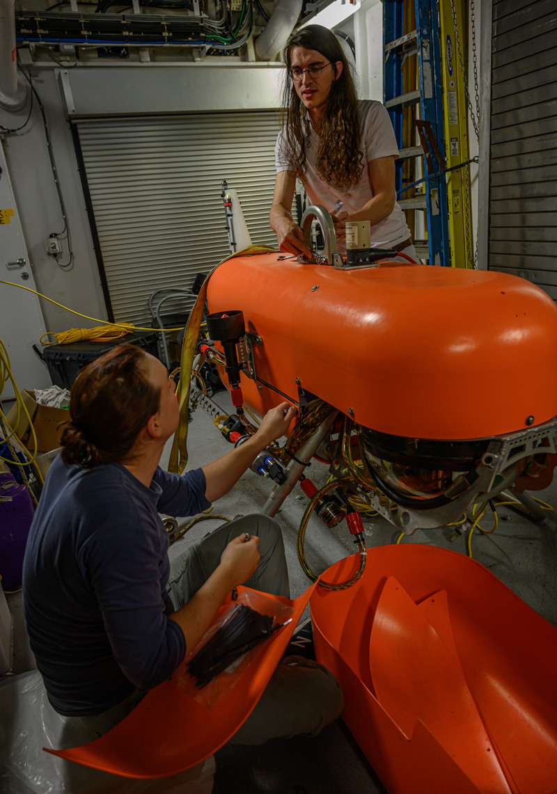 Woods Hole Oceanographic Institution  engineer Casey Machado (left) and NASA Jet Propulsion Laboratory engineer Russell Smith prepare Orpheus for a 2019 expedition.