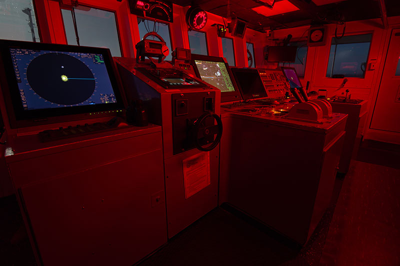 The bridge of NOAA Ship Okeanos Explorer at night. To help with navigation after sunset, lights on the bridge are dimmed and emit a red hue.