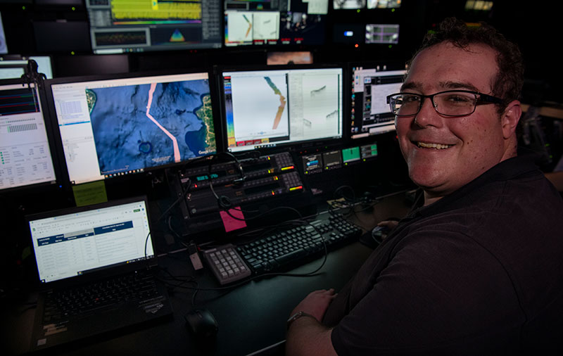 Henry Arndt, an Explorer-in-Training on the 2022 Caribbean Mapping expedition, reviewing collected expedition data in the control room of NOAA Ship Okeanos Explorer.