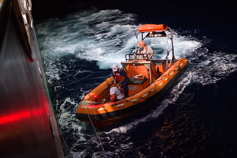 Members of the NOAA Ship Okeanos Explorer crew approach the ship after conducting small boat operations at night during the 2022 Caribbean Mapping expedition. Image courtesy of NOAA Ocean Exploration, 2022 Caribbean Mapping.