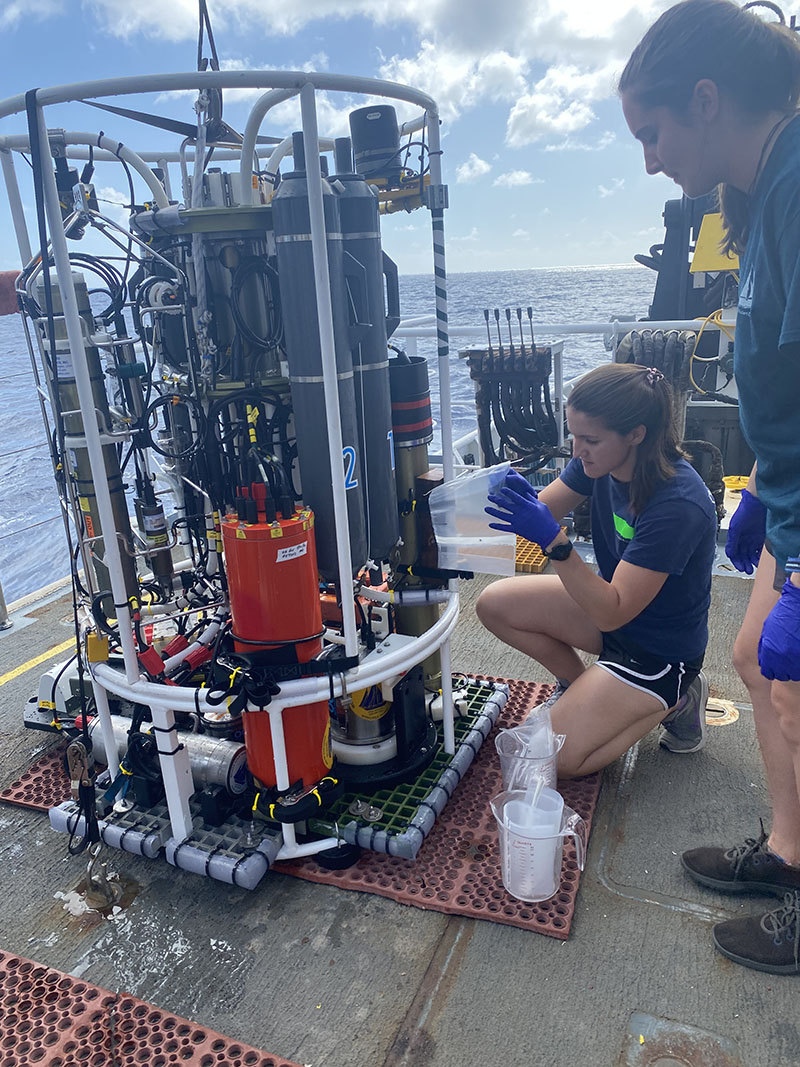 Scientists aboard NOAA Ship Okeanos Explorer during the 2022 Puerto Rico Mapping and Deep-Sea Camera Demonstration transfer water samples from the Niskin bottles on the conductivity, temperature, and depth (CTD) rosette to plastic bags so they can be transported to the ship's wet lab for processing.