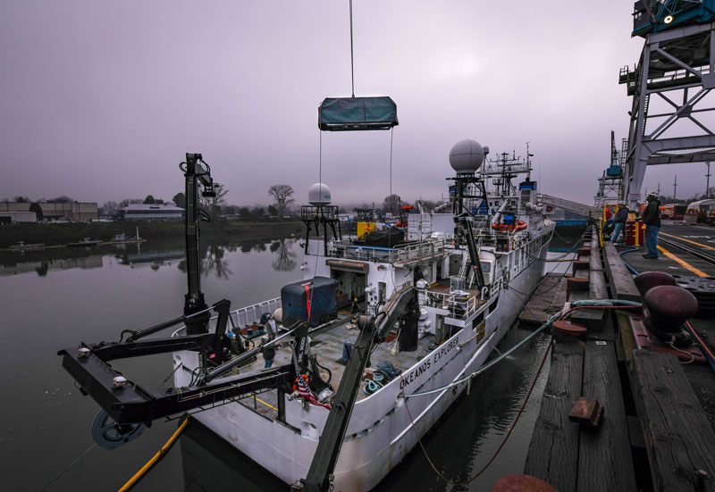 Remotely operated vehicle (ROV) Seirios is loaded onto NOAA Ship Okeanos Explorer in preparation for diving during the 2023 Shakedown + EXPRESS: West Coast Exploration expedition. ROV Deep Discoverer is visible on the back deck, covered in a blue tarp and waiting to be moved into its hangar.