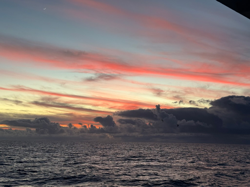 Image of the most breathtaking sunset on the Beyond the Blue: Papahānaumokuākea Mapping 1 expedition. You can spot two birds surfing the wind together in the direction of the sunset.