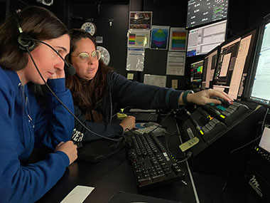 NOAA Ocean Exploration expedition coordinator team lead Shannon Hoy and explorer-in-training Adrianna Ebrahim in the control room on NOAA Ship <i>Okeanos Explorer</i>, processing multibeam bathymetry data collected during the Seascape Alaska 6 expedition.