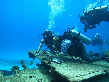 Divers using a small drill to measure corrosion on the wreck of the Japanese freighter Shoan Maru in the waters off Saipan in the Northern Mariana Islands during the Exploring Deepwater World War II Battlefields in the Pacific Using Emerging Technologies expedition.