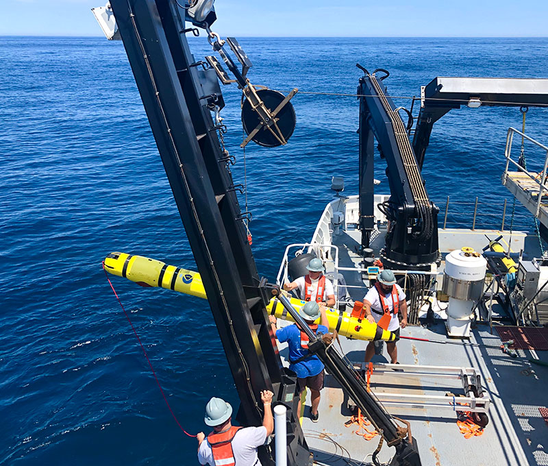 AB Peter Brill, AB Chris Remaley, GVA Sidney Dunn, and Acting CB Michael Collins recover the REMUS 600 using the J-frame on the CTD deck of the Okeanos Explorer.