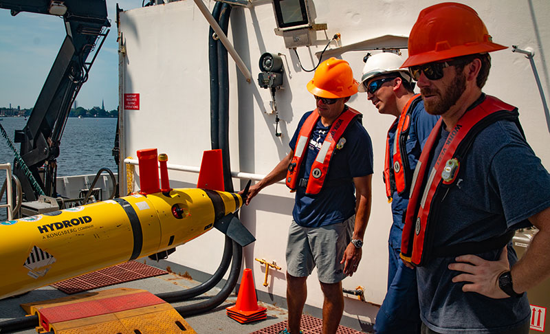 Alex Ligon, Lt John Kidd, and Mike Annis of NOAA's Office of Coast Survey plan how to launch and recover the REMUS 600 AUV while the Okeanos Explorer is pierside in Norfolk, Virginia.