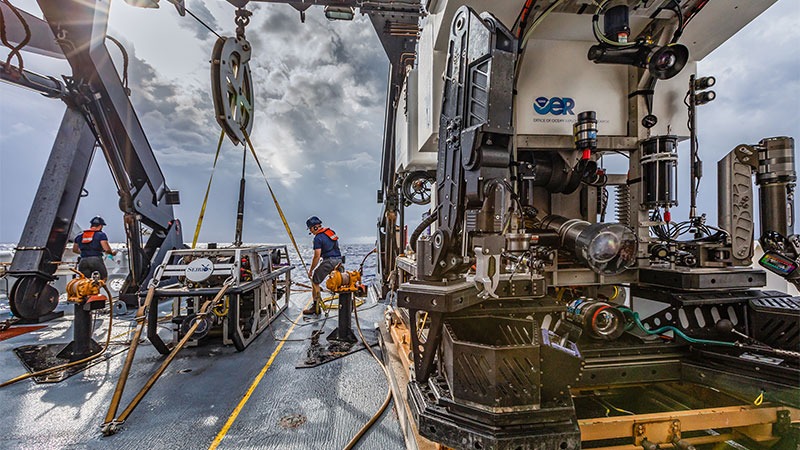The team preps Seirios and Deep Discoverer for the first remotely operated vehicle dive of the Windows to the Deep 2018 expedition on a cloudy morning. Image courtesy of Art Howard, GFOE, Windows to the Deep 2018.