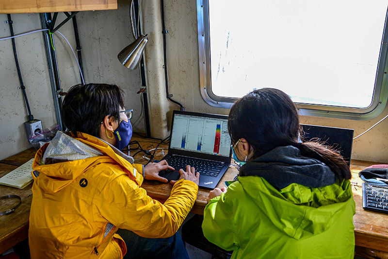 Principal investigator Wu-Jung Lee and research assistant Linda Nguyen analyze the data coming in from the ship&rsquo;s mounted echosounder. The graphs on their screens are called echograms and can be used to identify layers of small organisms in the water column.